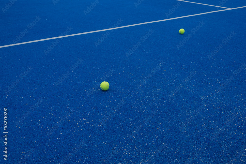 two balls on a blue paddle tennis court