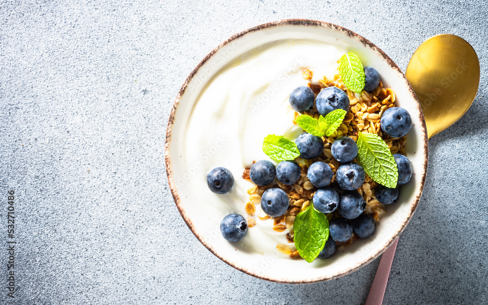 Yogurt with granola and fresh blueberry at light stone table. Healthy breakfast. Top view. Yogurt with granola and fresh blueberry at light stone table. Healthy breakfast. Top view.