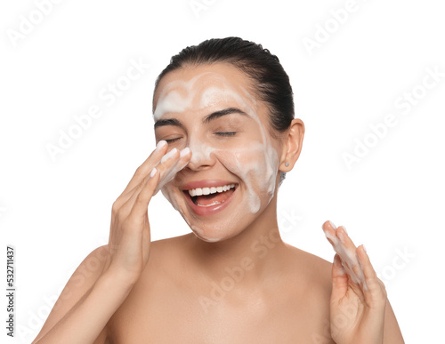Happy young woman washing face with cosmetic product on white background