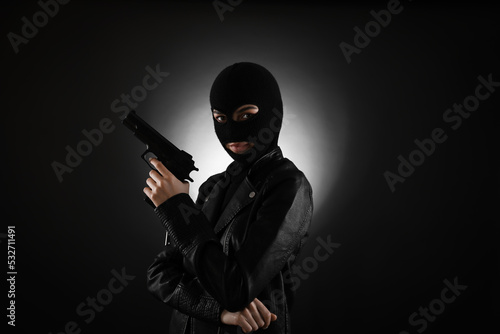 Woman wearing knitted balaclava with gun on black background