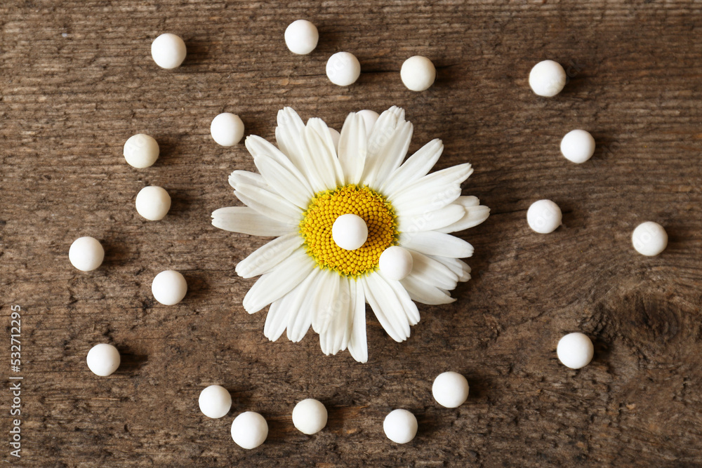 Fototapeta premium Homeopathic remedy and chamomile flower on wooden background, flat lay