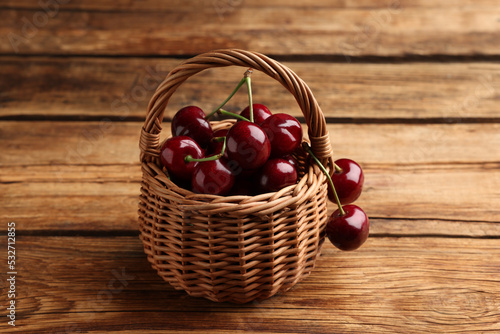 Bild auf Leinwand Wicker basket of ripe sweet cherries on wooden table