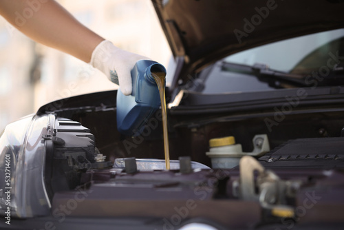 Man pouring motor oil from blue container, closeup. Space for text