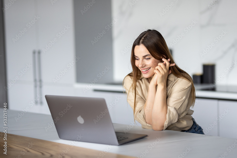 Happy young woman using laptop in cook room Happy young woman using laptop in cook room