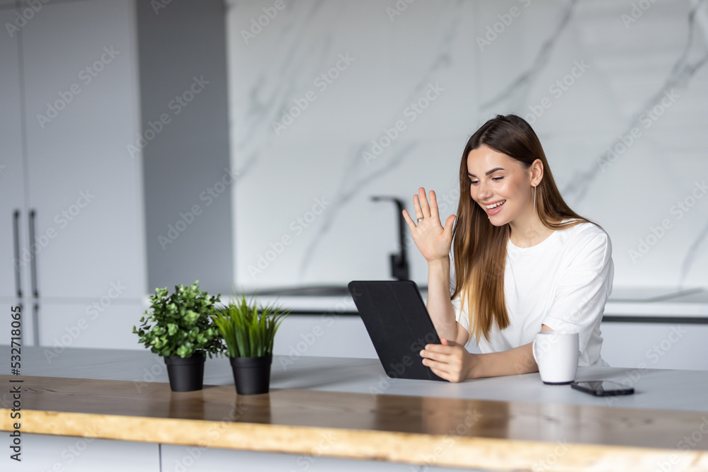 Cute woman make video call is smiling, looking into camera and holding tablet Cute woman make video call is smiling, looking into camera and holding tablet