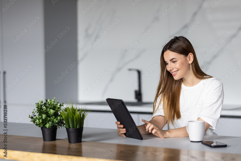 Young woman using a digital tablet in the kitchen Young woman using a digital tablet in the kitchen