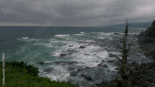 Panoramic view in area of Cape Velikan in southeast of Sakhalin Island, ocean waves wash shore of island in cloudy day photo