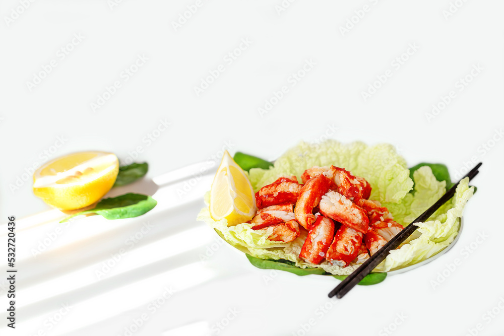 Seafood salad with juicy crab meat, fresh iceberg lettuce leaves and lemon on a white plate