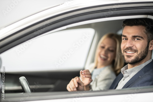 Shot of a cheerful beautiful couple sitting in a car together. Man kisses her hand © Panorama