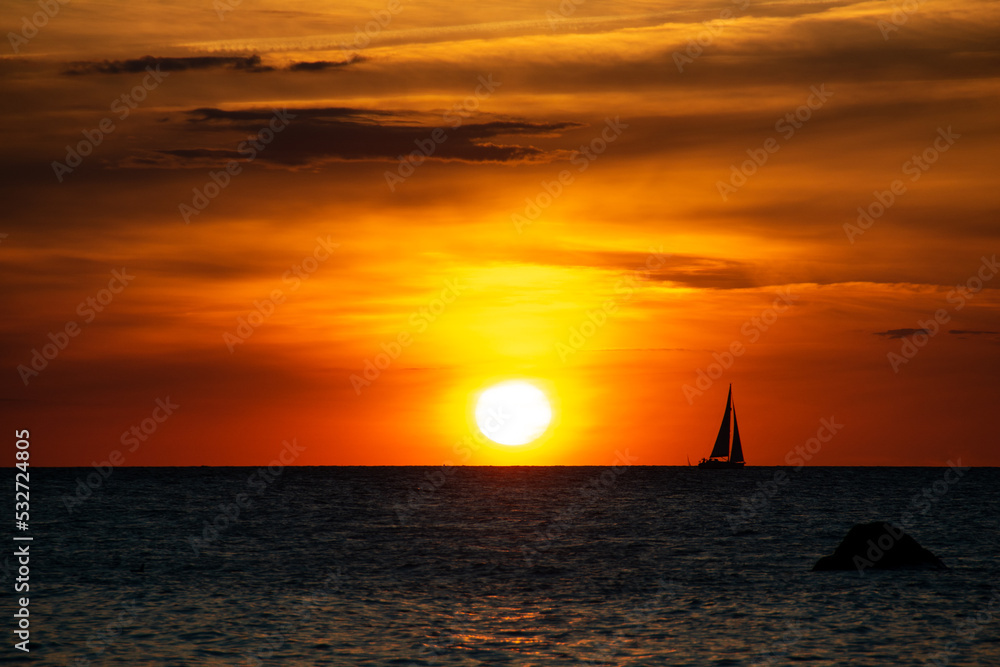 Sunset over the sea with a sailing ship on the horizon