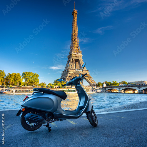Scooter parked by the Seine River in Paris with the Eiffel Tower in the background. France