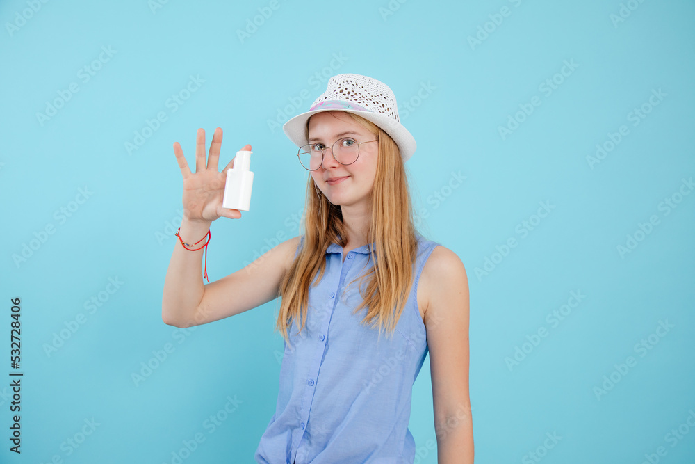 Portrait of cute teenage girl with long fair hair wearing glasses, showing white sunscreen cream on blue background. Portrait of cute teenage girl with long fair hair wearing glasses, showing white sunscreen cream on blue background.