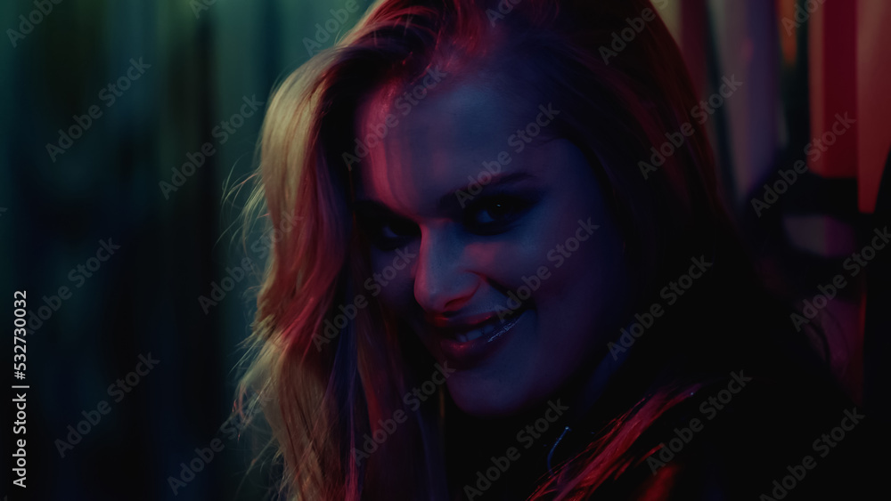 happy young woman smiling and looking at camera in nightclub.