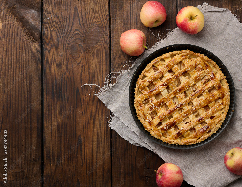 Round baked apple pie on a brown wooden table, top view Round baked apple pie on a brown wooden table, top view