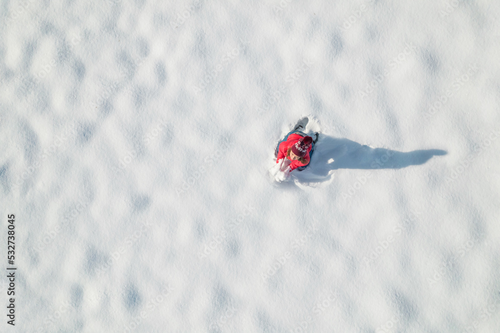 Woman in a red christmas jacket play snowballs on the snow in a park. Winter. Drone, top, aerial view.