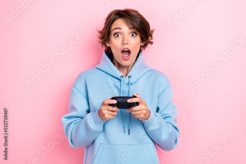 Photo of young attractive nice excited pretty girl wear blue hoodie open mouth shock hold gamepad player addicted isolated on pink color background
