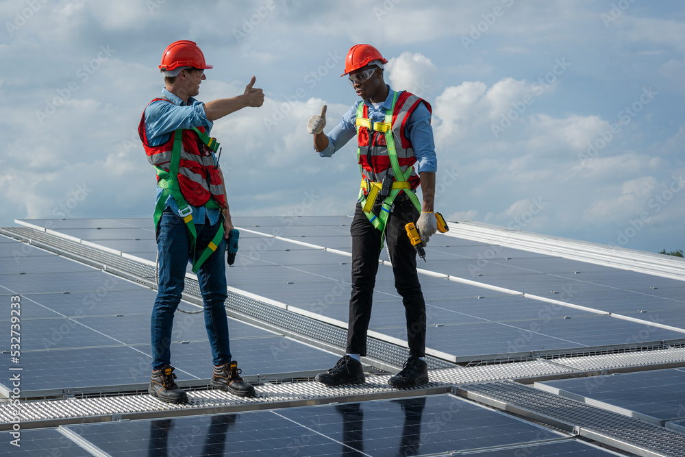 Technician wearing safety harness belt during installing the solar panels on roof structure of building factory,Economic energy and cost saving concept. Technician wearing safety harness belt during installing the solar panels on roof structure of building factory,Economic energy and cost saving concept.