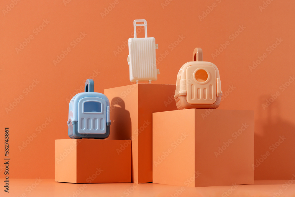 Concept travel or moving with animal, flight, safety. Plastic cage, pet carrier and suitcase on orange background Concept travel or moving with animal, flight, safety. Plastic cage, pet carrier and suitcase on orange background