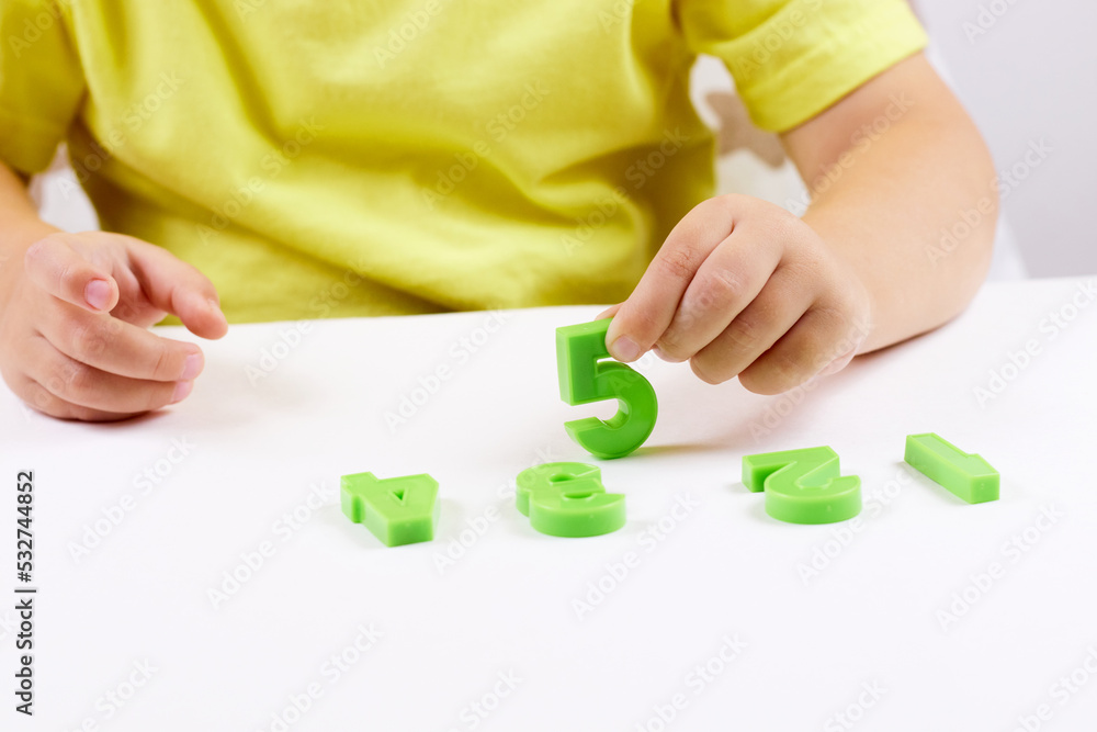 The child shows the number 5. Early development, playing with numbers, learning to count. selective focus The child shows the number 5. Early development, playing with numbers, learning to count. selective focus