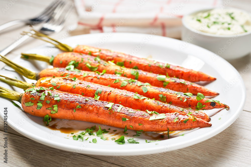 Roasted carrot with sauce in a bowl on a white wooden table. Caramelized Carrots. Close-up. Roasted carrot with sauce in a bowl on a white wooden table. Caramelized Carrots. Close-up.