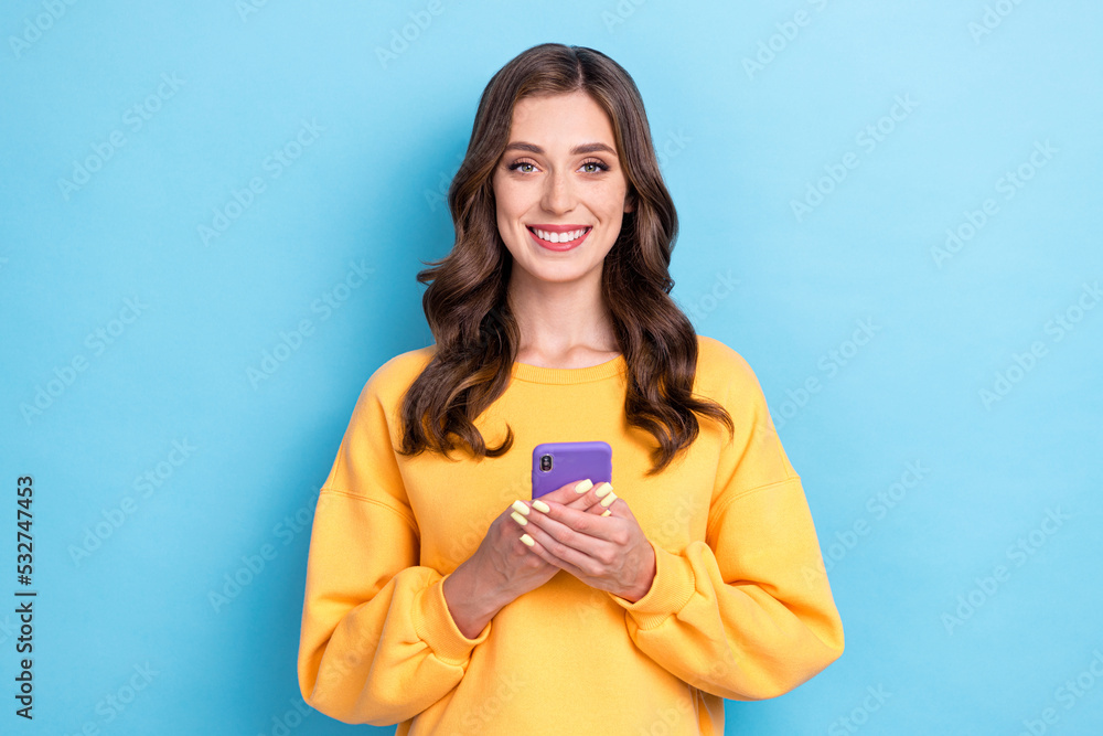 Photo of young adorable pretty gorgeous nice cute woman wear yellow shirt hold phone blogger youtube user isolated on blue color background Photo of young adorable pretty gorgeous nice cute woman wear yellow shirt hold phone blogger youtube user isolated on blue color background