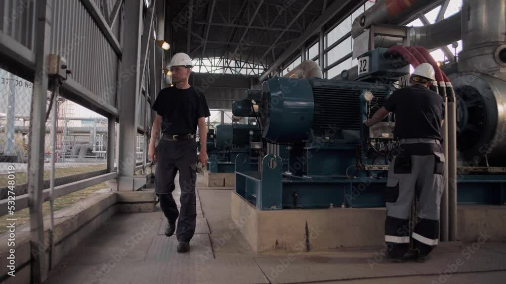 Professional engineers work at a pumping station with huge pumping units Professional engineers work at a pumping station with huge pumping units