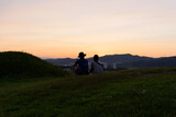 Lovely Couple sitting on the green hill to enjoy sunset