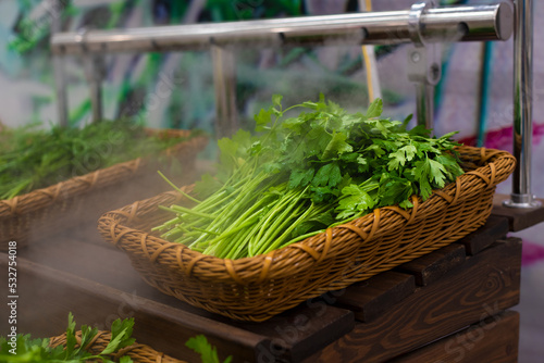 Greens on the counter of the store.Dill and parsley on a wooden table. blown with moisturizing steam