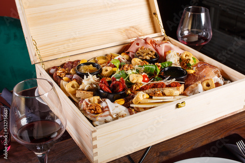 Aperitivo gigante con salumi, formaggi ed altri prodotti servito in una cassetta di legno e accompagnato da due calici di vino rosso in una braceria napoletana  photo