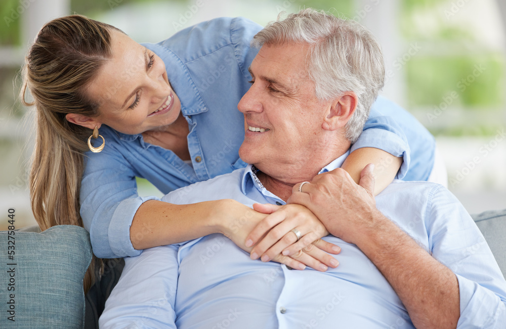 Happy senior dad with adult daughter on couch in home, quality time together in retirement with quality loving time. Young woman shows healthy, smiling father love and relaxing in living room