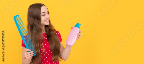 happy kid combing long hair. hairdresser. girl has wavy hairdo hold hairbrush. Kid girl hair care, horizontal poster. Banner header with copy space.