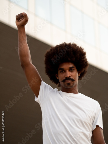 Print op canvas Young african american man with afro hair with fist raised as anti-racist symbol