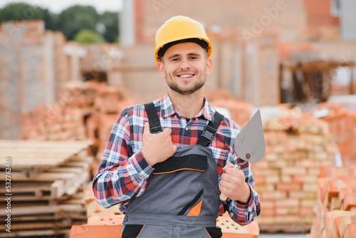 Obraz na plátně construction mason worker bricklayer installing red brick with trowel putty knife outdoors
