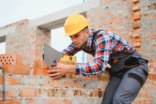 Installing brick wall. Construction worker in uniform and safety equipment have job on building photo