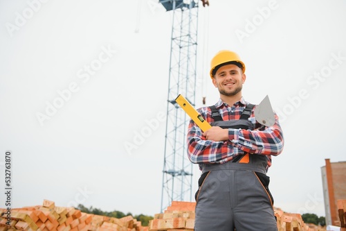 Fotografie construction mason worker bricklayer installing red brick with trowel putty knife outdoors