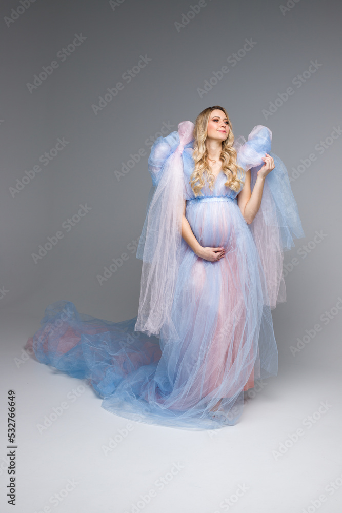 A young pregancy woman in blue dress. Maternity style. Vertical photo.