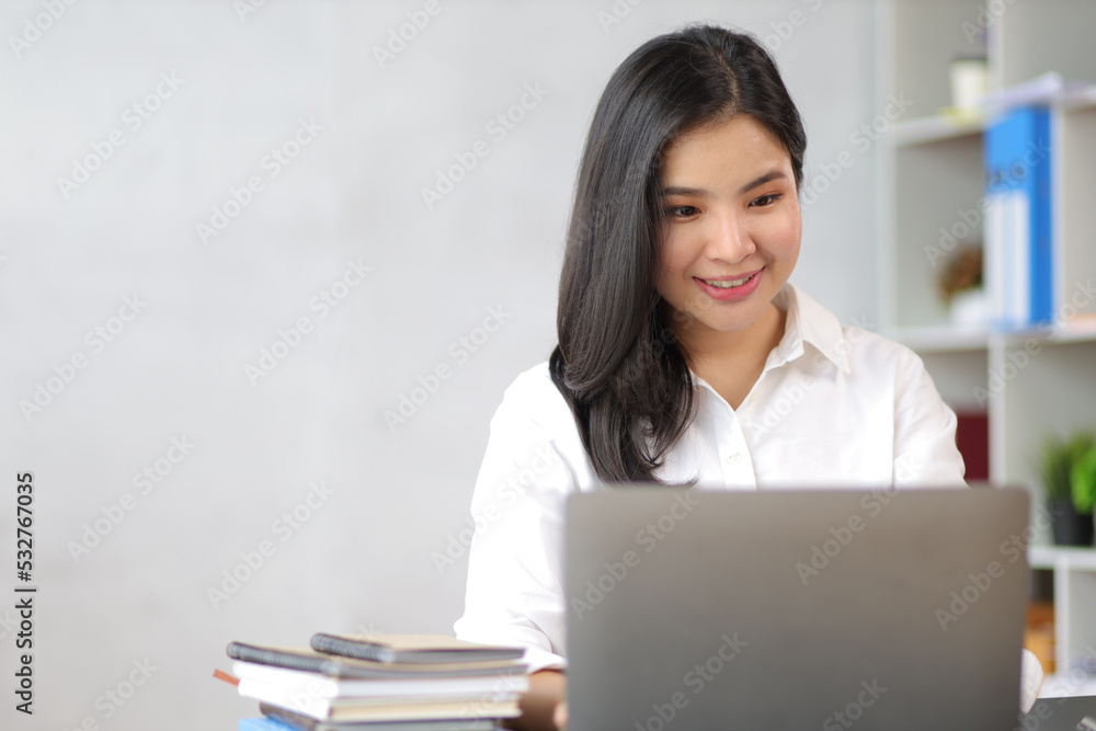 Portrait of a charming Asian business woman working on a laptop in the office. Portrait of a charming Asian business woman working on a laptop in the office.