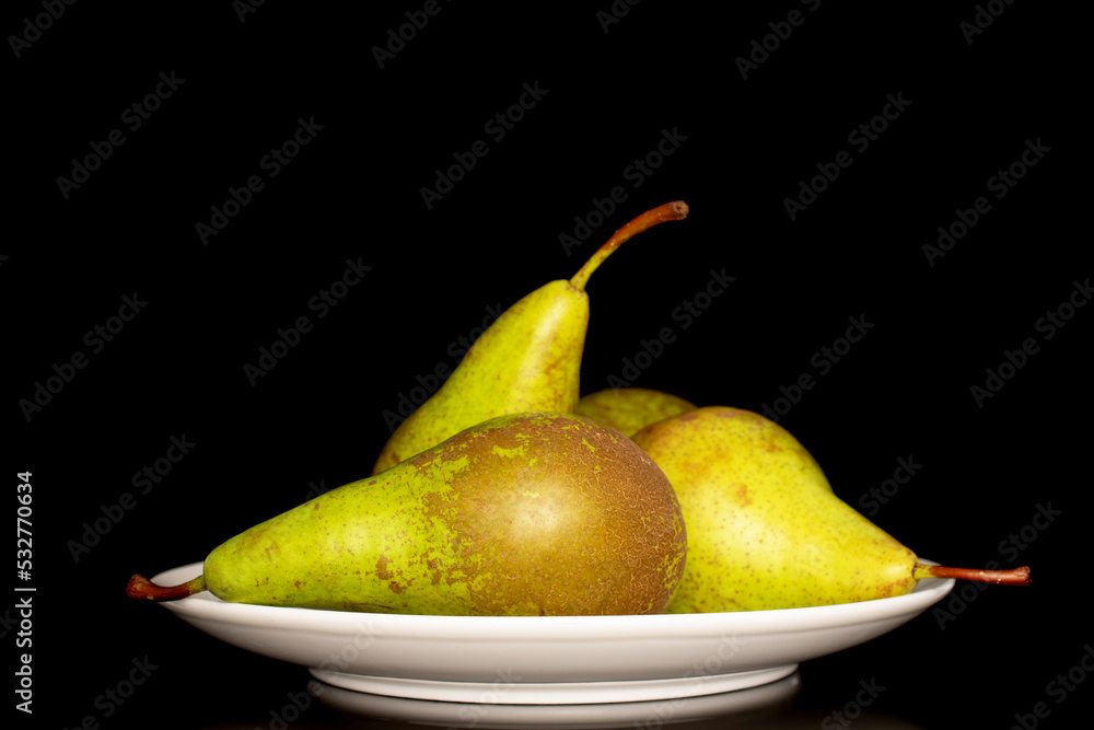 Three juicy organic pears in a white ceramic plate, macro, isolated on a black background. Three juicy organic pears in a white ceramic plate, macro, isolated on a black background.