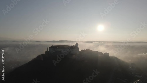 Medieval castle on top of a hill surrounded by mist at sunrise