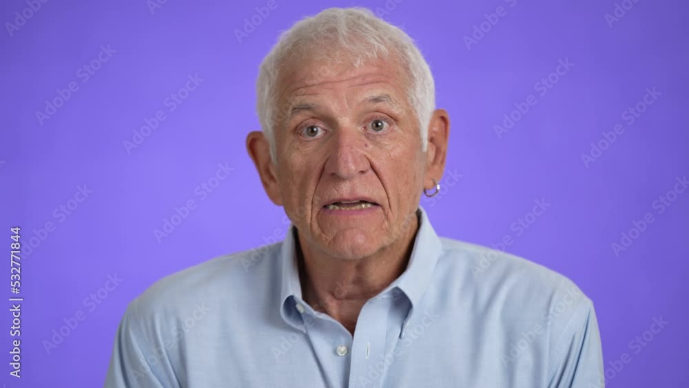 Handsome elderly man shaking head no, pensive mood, isolated on light purple background. Studio portrait. Handsome elderly man shaking head no, pensive mood, isolated on light purple background. Studio portrait.