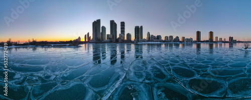 Photography defaultHorizontal wide angle aerial large panorama of frozen lake with Toronto Etobicoke neighborhood city skyline with highrise condo buildings in the background shot at sunset hour