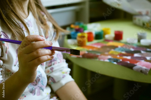 a child draws with paints multi-colored tones gouache brush