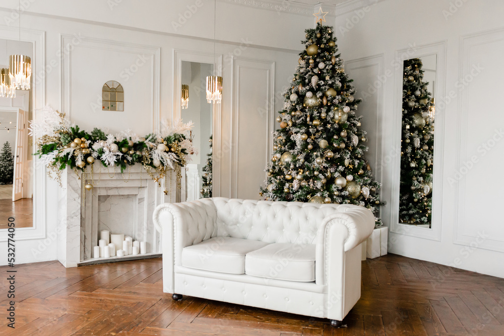 White Christmas room with a Christmas tree decorated with golden toys.