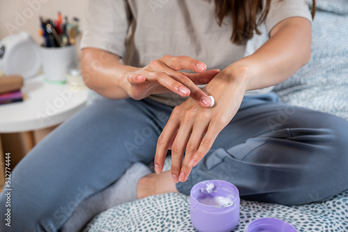 Young beautiful woman applying moisturize cream on her hands. Self care girl morning routine with skin care product for soft and nice skin protect.