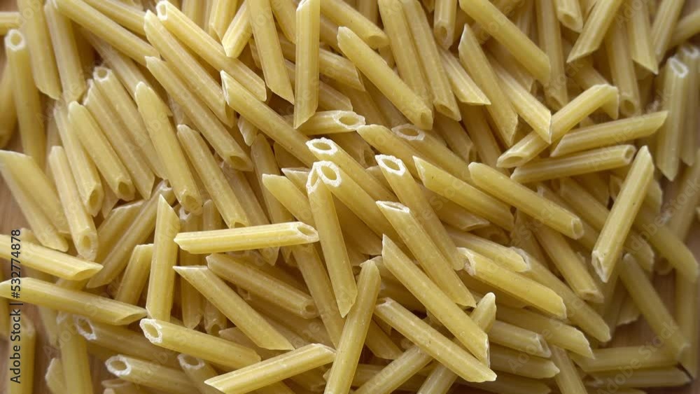 Raw italian penne rigate pasta isolated on wooden background Raw italian penne rigate pasta isolated on wooden background