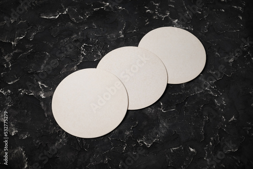 Three blank beer coasters on black plaster background. Responsive design template.
