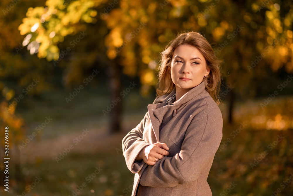A thoughtful woman in a warm coat against the background of autumn golden leaves. Autumn portrait A thoughtful woman in a warm coat against the background of autumn golden leaves. Autumn portrait