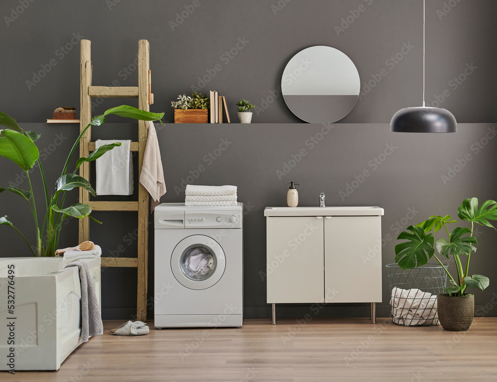 Modern bath room cabinet, sink, mirror and tub style grey wall background, vase of plant, laundry, towel and wooden stairs decorations. Modern bath room cabinet, sink, mirror and tub style grey wall background, vase of plant, laundry, towel and wooden stairs decorations.