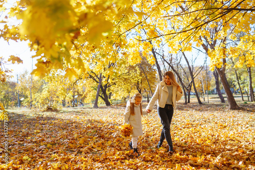 Young Mother and daughter walking in the park and enjoying the beautiful autumn nature. Rest, childhood, walk, family.