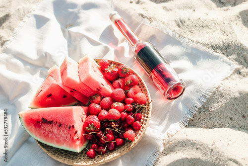 Champagne with a tray of fruits, strawberries and cherries on a picnic.